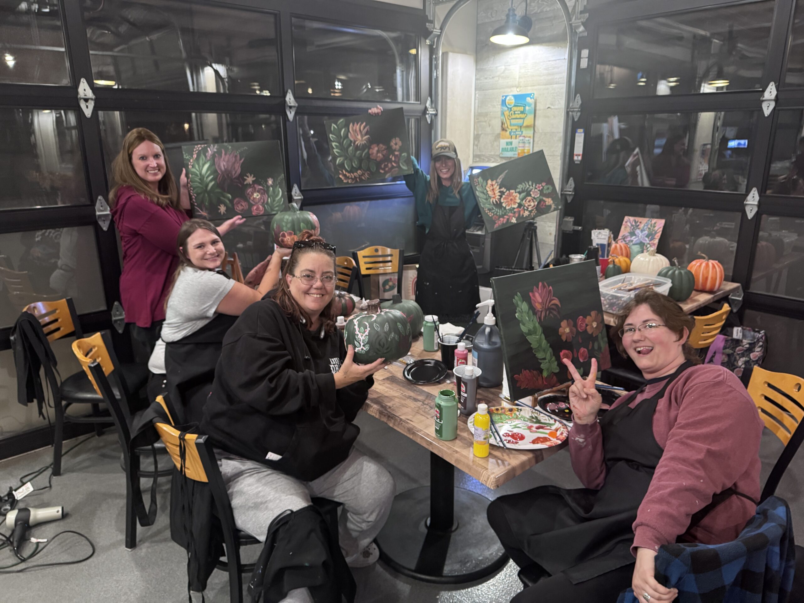 Fall Boho Paint Series guests showing their finished pumpkins and canvases
